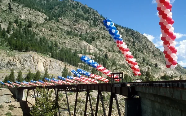 Red, white, and blue balloon arches decorating the Georgetown Loop Railroad high bridge with Rocky