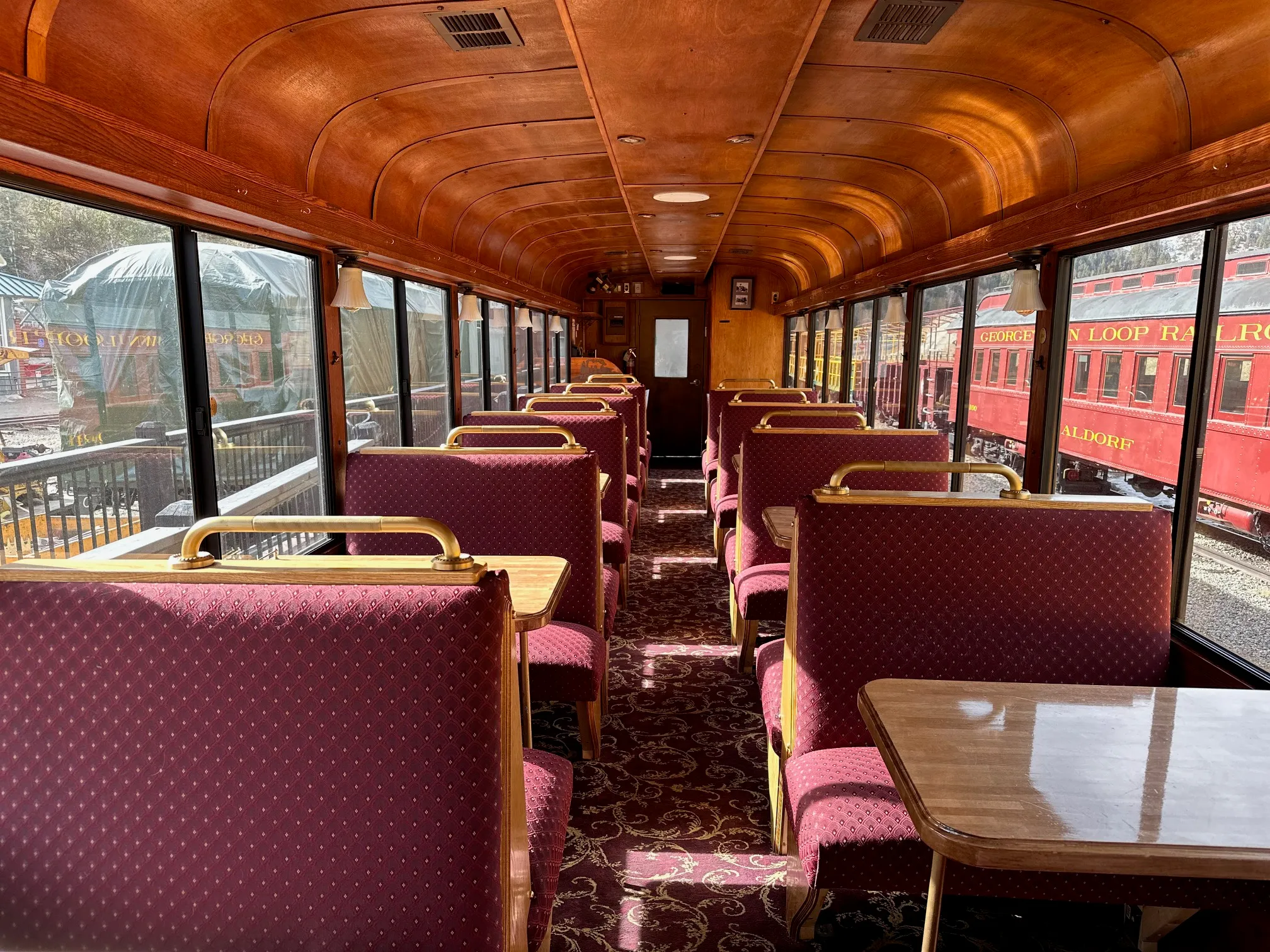 Elegant booth seating inside the Georgetown Loop parlor car with polished wood ceiling, brass