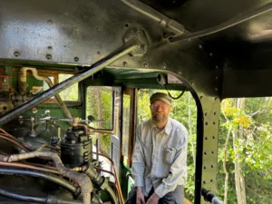 Georgetown Loop Railroad engineer standing inside the cab of a steam locomotive surrounded by