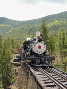 Front view of a Georgetown Loop steam locomotive with its headlight glowing, approaching on the