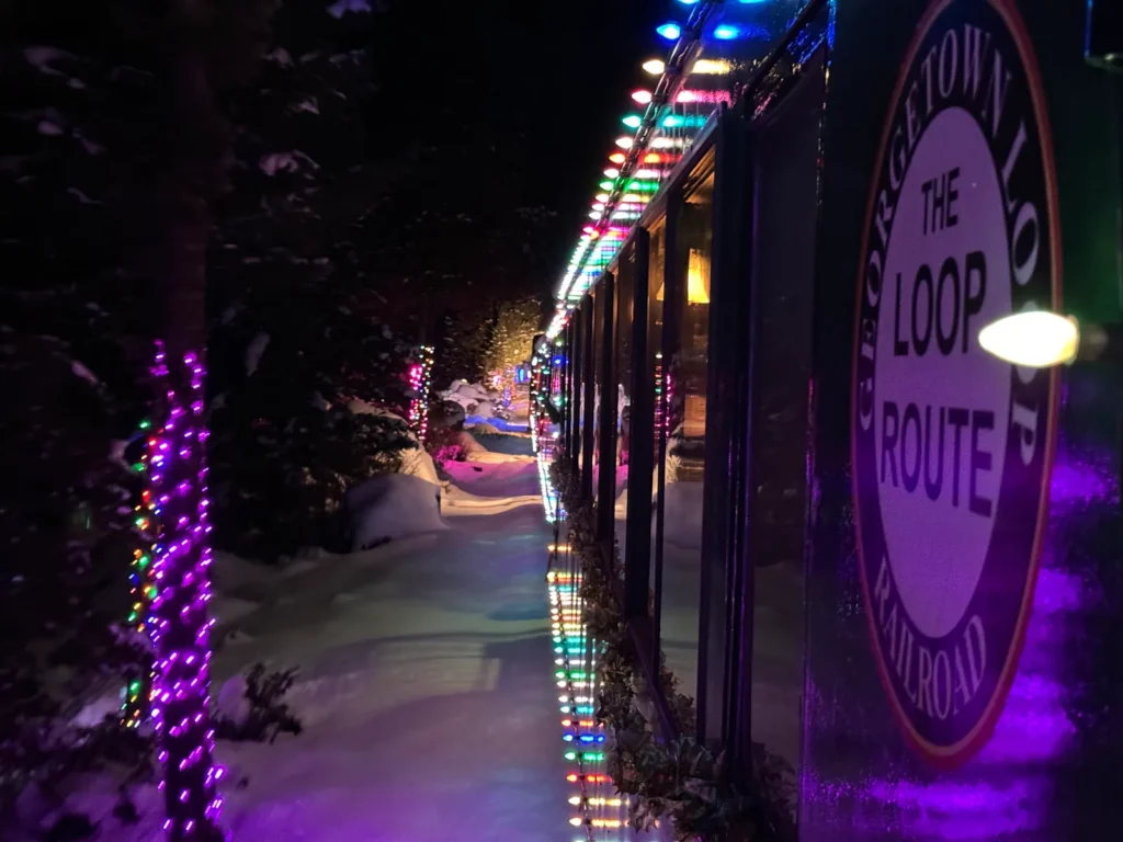 Georgetown Loop Railroad Winter Holiday Train decorated with colorful Christmas lights traveling through snowy Colorado night