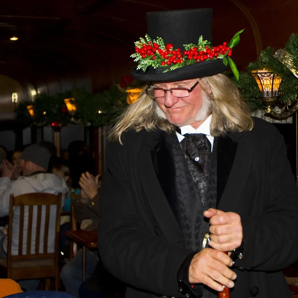 Victorian costumed entertainer with holly-decorated top hat performing aboard Georgetown Loop Winter Holiday Train