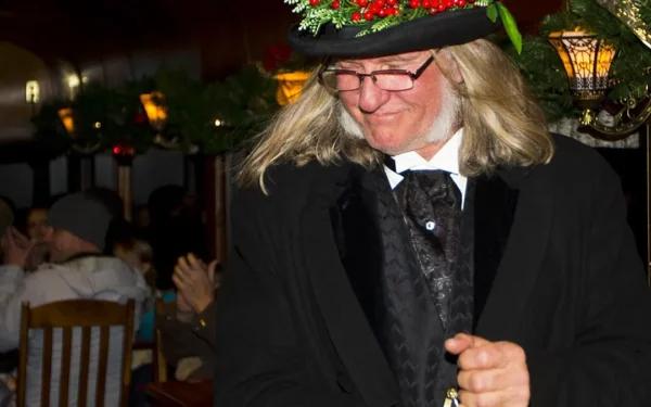 Victorian costumed entertainer with holly-decorated top hat performing aboard Georgetown Loop